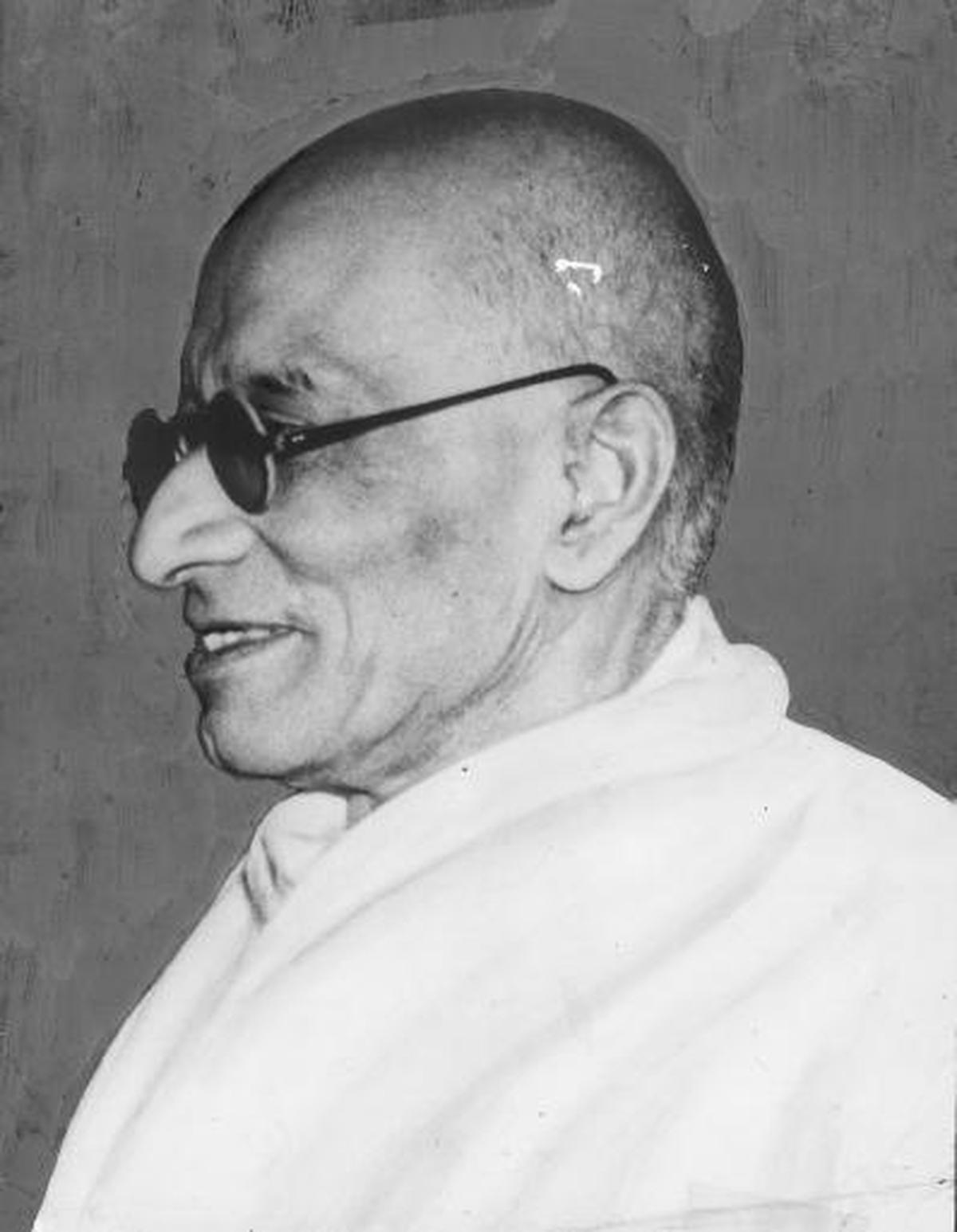 C. Rajagopalachari in profile, wearing dark round glasses and a khadi shawl.