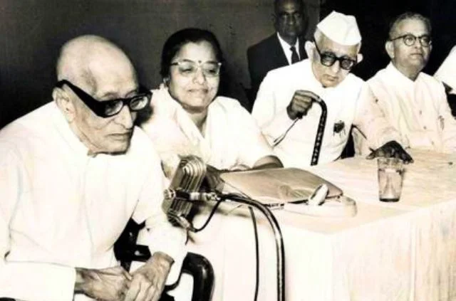 Elderly C. Rajagopalachari speaking at a microphone from a shared dais.